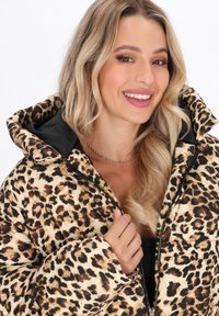 Leopardenmuster Pufferjacke mit glänzender Oberfläche, schwarzen Akzenten, einem Reißverschluss vorne und einer großen Kapuze, die eine gesteppten Struktur präsentiert.