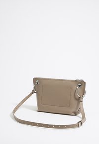 Borsa a tracolla in pelle beige con superficie texturizzata, chiusura superiore con zip e dettagli in hardware circolare argentato. Inclusa una tracolla regolabile.