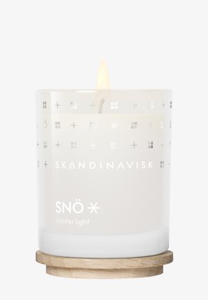 Bougie blanche brûlante dans un porte-bougie en verre avec des symboles scandinaves et le texte "SNÖ Lumière d'hiver" sur une base en bois.