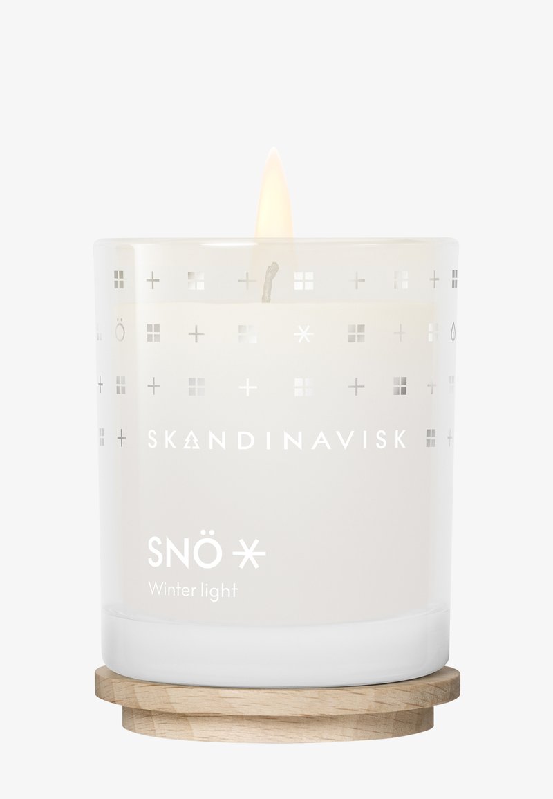 Brinnande vit ljus i en glasbehållare med skandinaviska symboler och texten "SNÖ Vinterljus" på en trähylla.