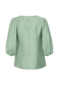 Blusa verde pallido con finitura testurizzata, scollatura tonda e maniche a sbuffo che si restringono ai polsi. Design semplice e privo di decorazioni.