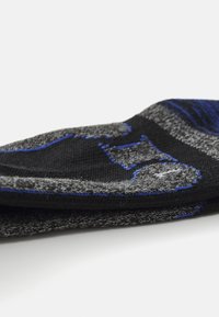 Črne in sive nogavice z modrimi poudarki, ki imajo teksturiran vzorec. Tkanina izgleda elastična in mehka. Oblikovanje vključuje plasten videz.