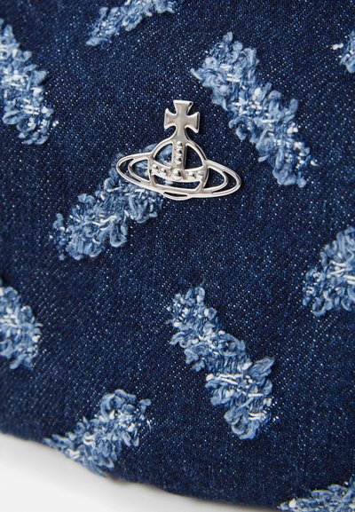 Denim fabric features a dark blue base with light blue textured embroidery in clusters. A silver metal logo with cross and orbit design.