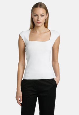 Haut blanc ajusté avec un décolleté carré et des manches courtes, fabriqué à partir d'un tissu texturé, associé à un pantalon noir.