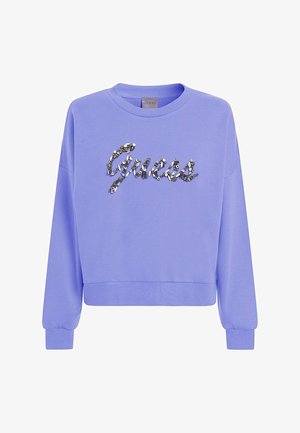 Sudadera de manga larga en color lavanda con puños y dobladillo acanalados, que presenta el logo de "Guess" escrito en brillantes piedras de strass plateadas decorativas en el pecho.