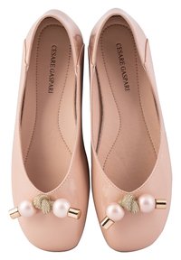 Ballerines en cuir verni rose clair avec un bout arrondi, ornement circulaire en perles et en ton doré sur le devant, et semelle intérieure texturée.