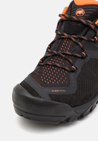 Zwarte wandelschoen met oranje accenten, voorzien van ademende mesh-panelen, gestructureerde suède overlay en een duurzame rubberen zool.