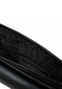 Portafoglio in pelle nera con chiusura a zip. L'interno presenta un rivestimento testurizzato con motivo di branding ripetuto. Include una piccola tasca con zip.