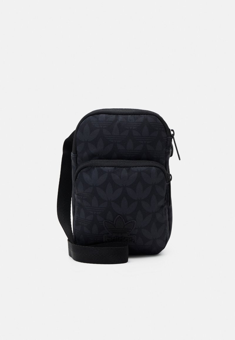Sacoche noire compacte d'Adidas avec un motif trefoil subtil, poche zippée à l'avant et bandoulière réglable.