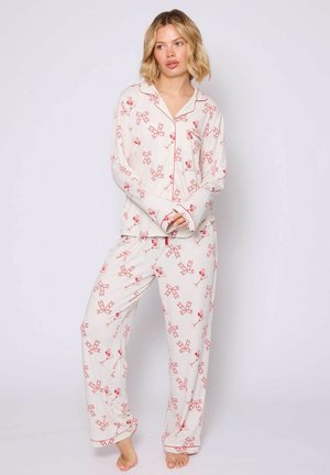 Wit pyjama set met een rood strik en kersenpatroon. Zachte stof met lange mouwen, een knoopsluiting aan de voorkant en losse broekspijpen.