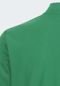 Maglietta polo verde con una finitura tessuta e strutturata. Presenta un colletto classico e maniche corte, evidenziando un design pulito e semplice.