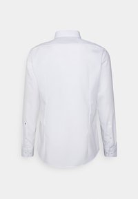 Witte overhemd met lange mouwen en een klassieke kraag. Gladde textuur, afgeronde onderkant en met knopen afgesloten manchetten. Geen zichtbare patronen of accenten.
