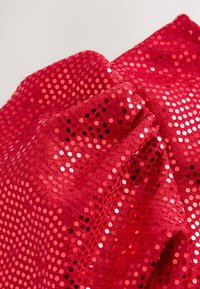 Rødt paliettekstilet med en tekstureret overflade, der har cirkulære palietter i forskellige nuancer af rød, hvilket skaber en glitrende effekt.