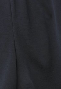 Tissu bleu marine foncé avec une texture lisse, présentant de légers plis et rides, indiquant un vêtement ou un produit textile drapé.