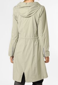 Jasnozielony wodoodporny płaszcz z regulowanym paskiem w talii, kapturem oraz zapinanymi na zamek mankietami; posiada rozcięty dół dla swobody ruchów.