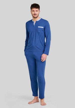 Top azul de manga larga con un cuello y un bolsillo azul claro, combinado con pantalones azules a juego. Tejido suave y liso con un diseño ajustado.