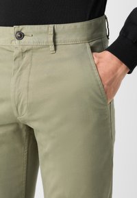 Ljusgröna bomullbyxor med en mjuk textur, med framfickor och knappstängning i midjan.