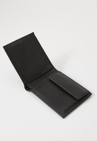 Portafoglio in pelle nera con più slot per carte, una patella per il portacarte e cuciture eleganti, caratterizzato da una texture liscia e un design minimalista.
