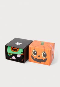 Coffret de chaussettes sur le thème d'Halloween dans une boîte noire et orange. Chaussettes vertes avec un motif de citrouille, chaussettes noires avec des motifs colorés.