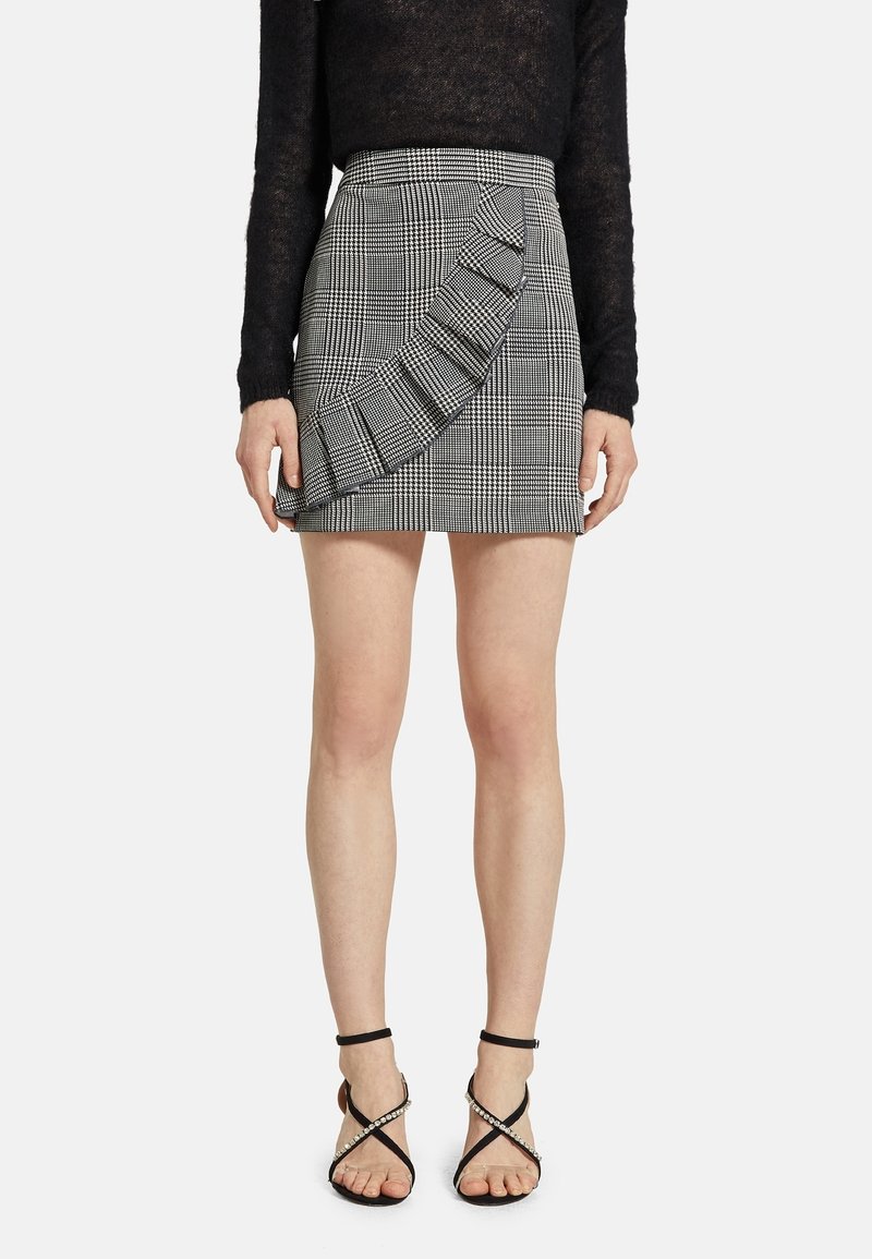 Černobílá kostkovaná sukně s volánkovými detaily na jedné straně, se zvýšeným pasem a rovný střih. V kombinaci s černými sandály na tenkých páscích.