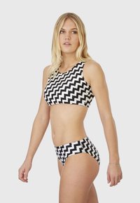 Black and white zigzag-patterned bikini set featuring a cropped top and high-waisted bottom, made from textured fabric.