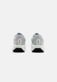 Une paire de chaussures de sport grises avec des semelles intermédiaires blanches et des semelles extérieures noires, présentée de l'arrière contre un fond blanc uni.