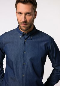 Donkerblauwe denimhemd met een button-down kraag, drie knopen aan de voorkant en lange mouwen. Gladde textuur en casual ontwerp.