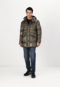 Veste rembourrée en vert olive métallique, avec une fermeture éclair à l'avant, un bouton de fermeture, une capuche et plusieurs poches avant. Texture lisse et design matelassé.