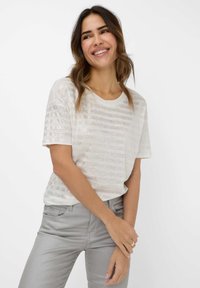 Lichte, korte mouwen top in crème met subtiele horizontale strepen. Gemaakt van een gestructureerde stof, gecombineerd met lichtgrijze broek.