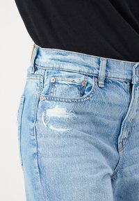 Gai zili džinsi ar nolietotu dizainu, ar plēsumiem un saplēstiem malām. Klasiska piecu kabatu stila un standarta jostasvieta.