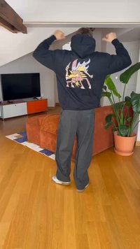 Sudadera negra con un gráfico colorido de un unicornio en la espalda; material de algodón, corte relajado, combinada con pantalones gris oscuro, en interiores.