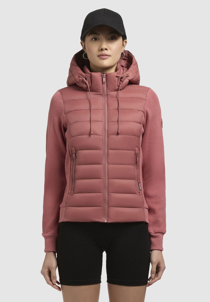 Gepofte roze jasje met een capuchon en rits aan de voorkant, met een gladde romp en zachte mouwen, vergezeld van ritszakken aan de zijkanten.
