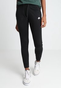 Svarta tapered sweatpants med elastiska muddar, dragsko i midjan och en liten vit Nike-logga på vänster lår. Material av bomullsblandning.