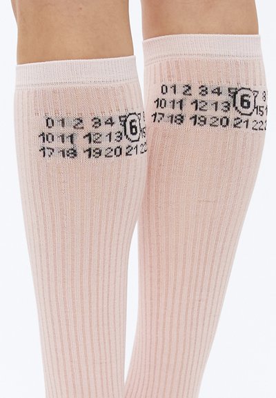Podkolienky s rebrovaným vzorom v jemnej ružovej farbe s čiernym číselným dizajnom a logom vytlačeným blízko hornej časti. Materiál pôsobí pružne a ľahko.