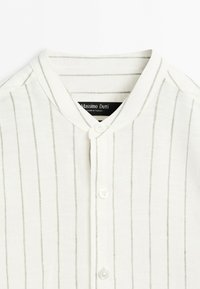 Chemise blanche boutonnée avec fines rayures verticales et col rond de Massimo Dutti, fabriquée en Turquie.