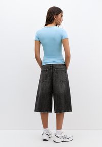 Világoskék, testhezálló póló laza, sötétszürke farmer culottessal párosítva. Az öltözet egyszerű dizájnnal és kontraszt varrással rendelkezik.