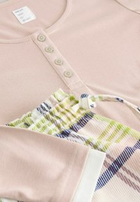 Light pink long-sleeve top with four buttons at the neckline, paired with green and blue-striped pajama shorts with a drawstring.