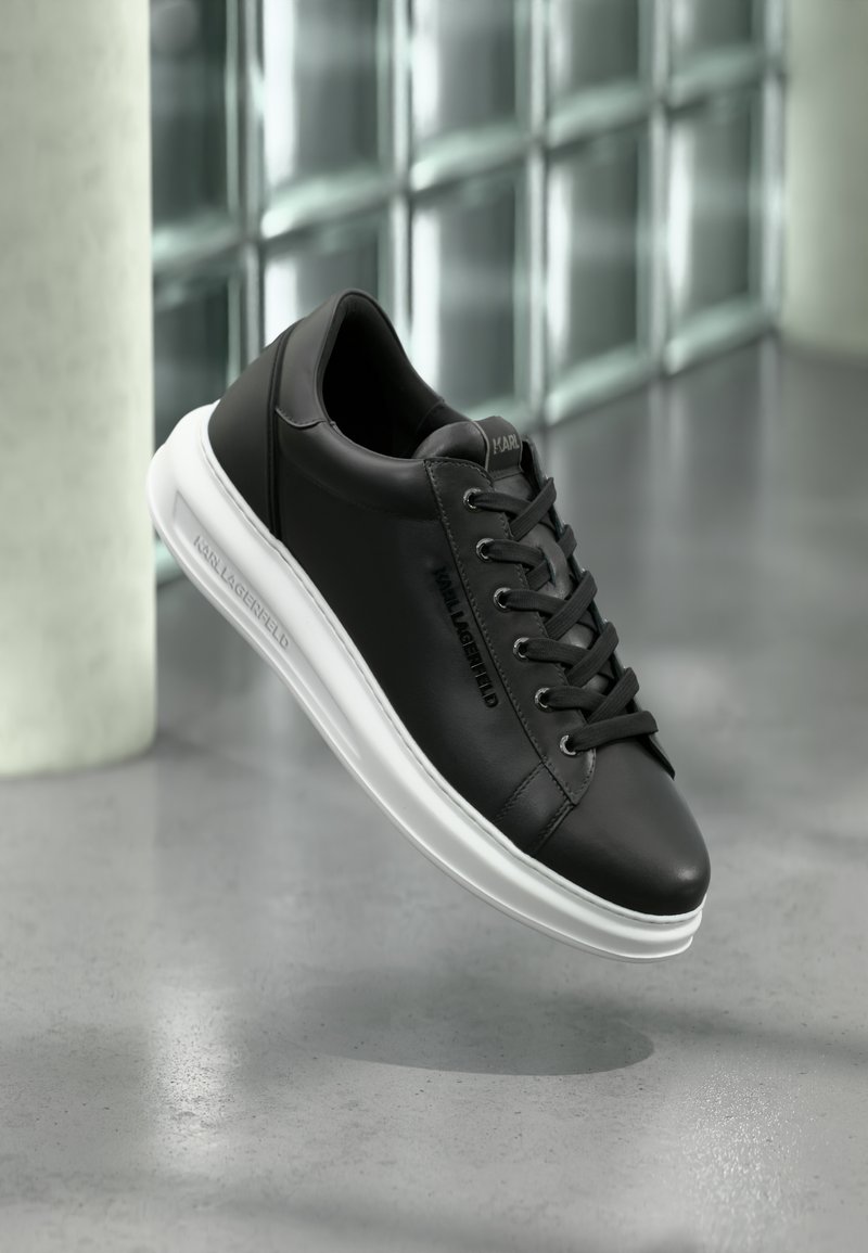 Tenisi din piele neagră cu o textură netedă, talpă din cauciuc alb și șireturi negre plate. Au branding-ul "KARL LAGERFELD" pe lateral.