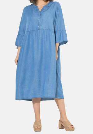 Dżinsowa sukienka midi z plisą zapinaną na guziki, dekoltem w kształcie litery V i rękawami typu bell o długości 3/4. Posiada marszczoną talię oraz boczne rozcięcia zapewniające swobodę ruchów.