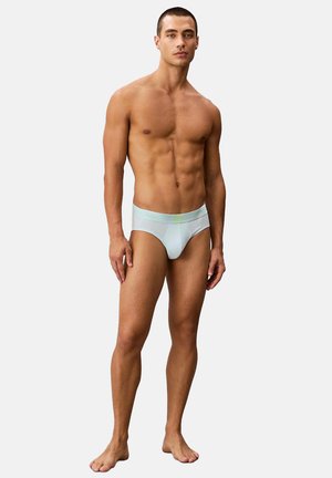 Slip da uomo azzurro chiaro con una morbida fascia in vita impreziosita da un logo verde neon, realizzati in un tessuto liscio ed elastico con un design aderente.