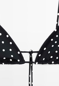 Haut de bikini triangle noir à pois blancs, noué avec de fines bretelles en nœud au centre devant.