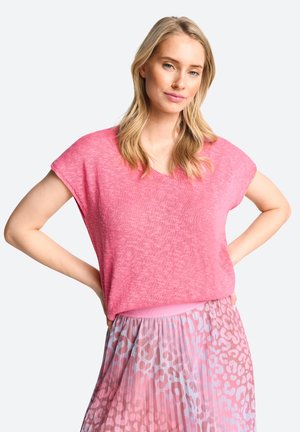 Roze gebreide top met korte mouwen en een v-hals. Gecombineerd met een pastelgradiënt rok met een subtiel luipaardprintpatroon.