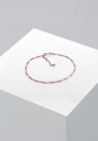 Armbandet av roséguld har en tvinnad design med små pärlindsatser och en justerbar låsning för varierad storlek.