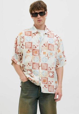 Short-sleeved button-up shirt featuring a patchwork design in red, blue, and orange floral patterns on a light background.