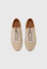 Beige sneakers med overdel i semsket skinn, snøring og lysegrå detaljer. Har gummisåle og en enkel logo på tungen.