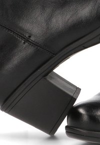Botas de cuero negras hasta el tobillo con un bajo tacón cuadrado. Textura suave, con detalles de costura mínimos y diseño de punta redonda.