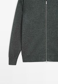 Maglione grigio scuro con zip, realizzato in un morbido tessuto a maglia, dotato di maniche lunghe, colletto alto e polsini e orlo a costine.