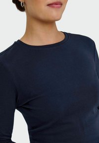 Top de manga larga azul marino con cuello redondo, hecho de una suave mezcla de algodón, con textura suave y silueta ajustada.