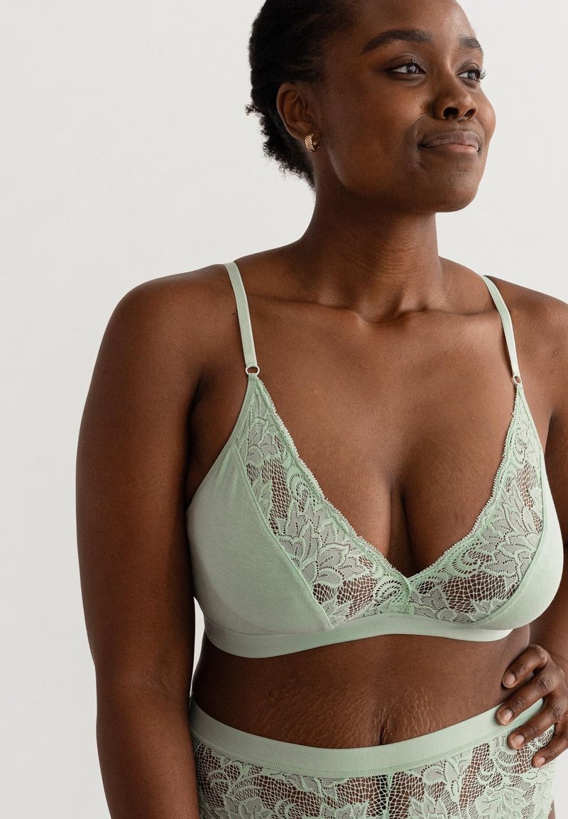 Mintgroene bralette met kantaccenten, verstelbare bandjes en een diepe halslijn. Zachte stof met een gladde textuur en bloemenpatroon.