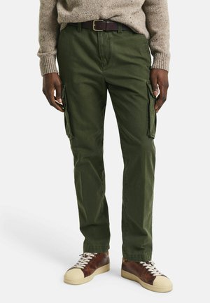Olijfgroene cargobroek, gemaakt van stevige stof, met zijzakken en een rechte pasvorm. Gecombineerd met bruin en crème sneakers.